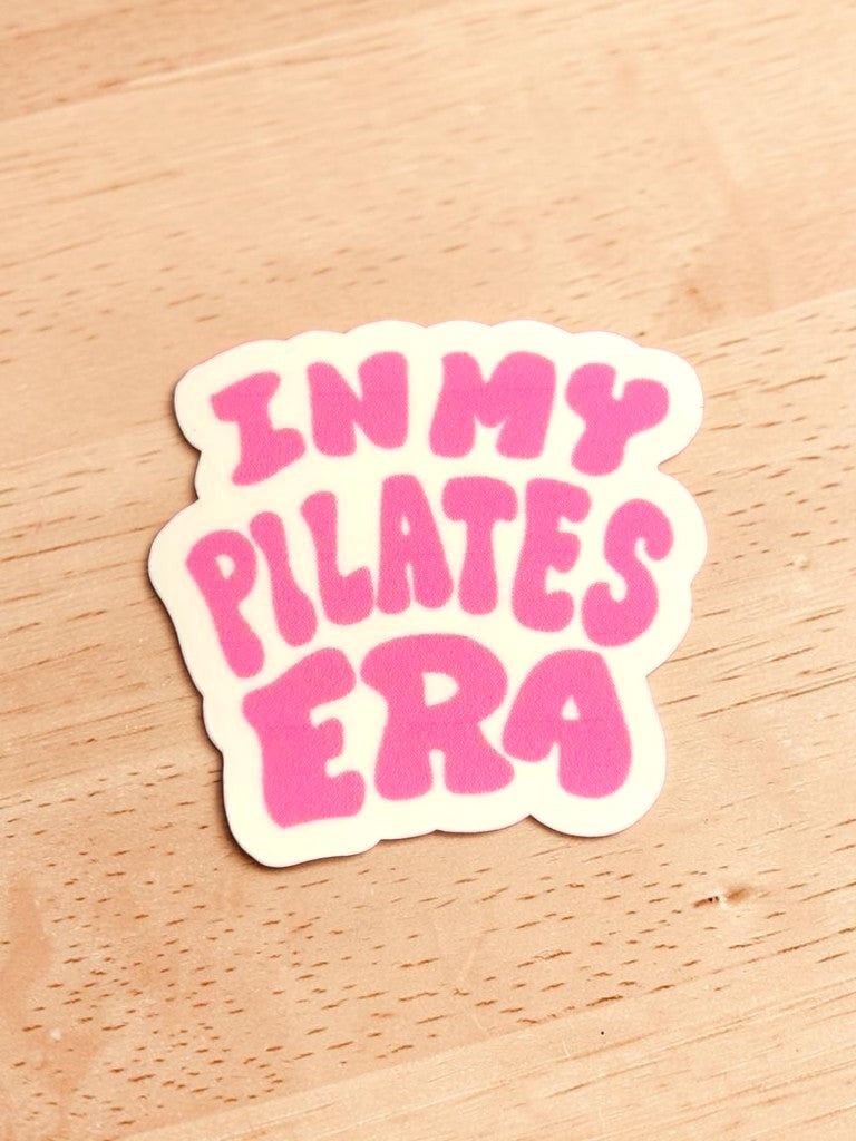 Permanent Sticker with 'IN MY PILATES ERA' text in pink on a wooden surface