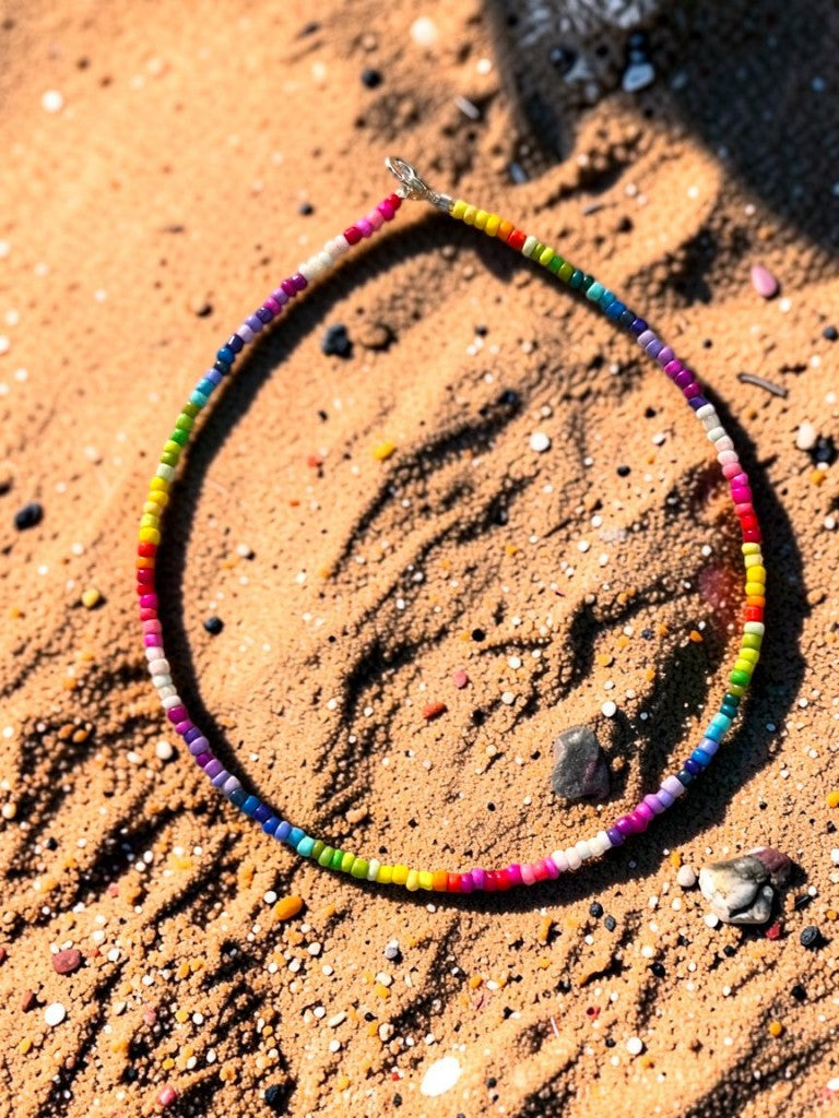 Colorful beaded necklace on a sandy surface