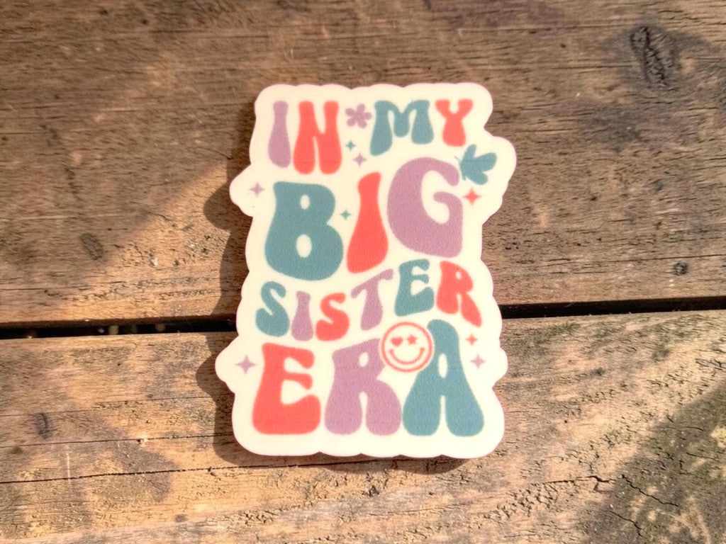 Colorful sticker with 'In My Big Sister Era' text on a wooden surface